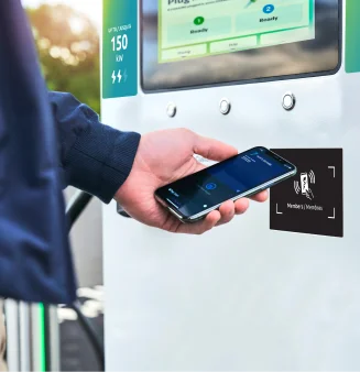 Closeup of a person tapping a smartphone to the charging station’s RFID reader.